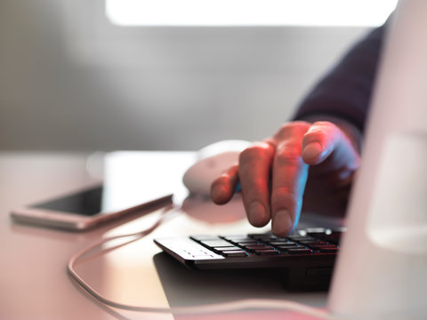 Computer hacker at laptop computer with mobile phone