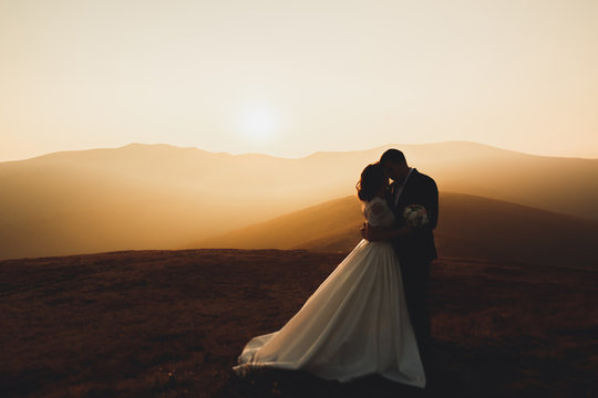 Wedding couple posing on sunset at wedding day. Bride and groom in love