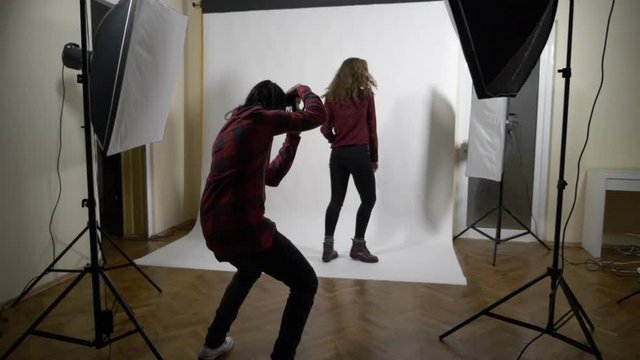 Behind the scenes photo shoot session of a blonde curly slim model for a famous clothing brand in a professional studio with white background in slow motion