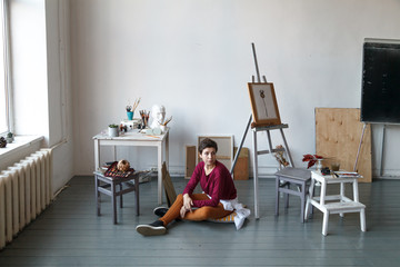 Female artist in her spacious white studio working with watercolor painting.  Natural lighting. Disclosure of creativity concept. Horizontal composition with copy space.