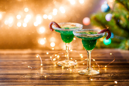 Christmas picture of two wine glasses with green cocktail, caramel sticks and garland