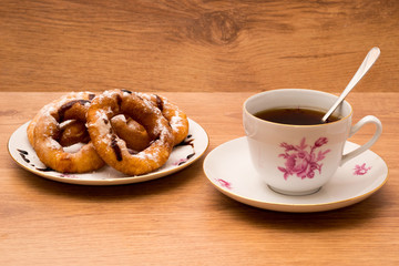 Завтрак. Чай и тарелка с пончиками. На деревянном фоне