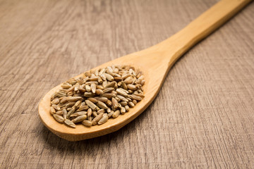 Rye cereal grain. Spoon and grains over wooden table.
