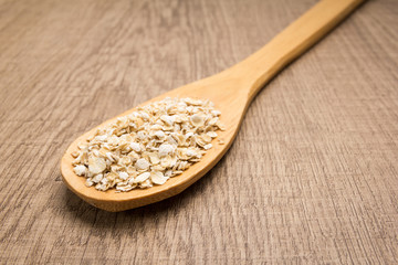 Oat cereal grain. Spoon and grains over wooden table.