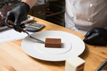 Cropped view of chef placing cake on plate