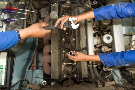 Overhead view of car mechanics hands and car engine in repair garage