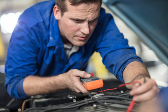 Car mechanic testing car engine in repair garage