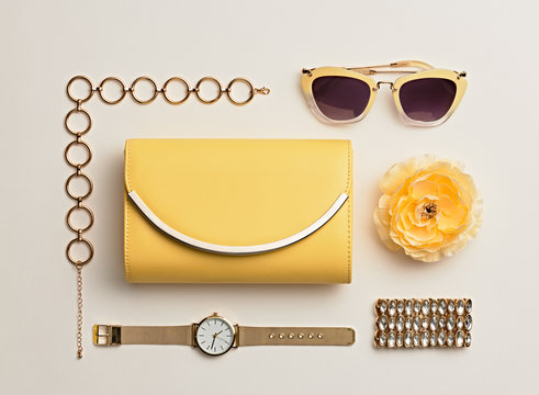 Fashion. Woman Accessories Set. Trendy Gold Watch, Summer Sunglasses, Glamour fashion Yellow Clutch. Flower. Flat lay. Luxury Stylish Spring lady. Pastel Color