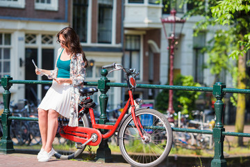 Obraz premium Happy young woman with a city map on bike in european city