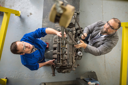 Overhead view of  car mechanics hoisting car engine in repair garage