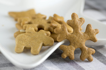 Traditional tasty Czech gingerbreads, Christmas snowflakes and reindeer on white star shaped plate on grey chequered tablecloth