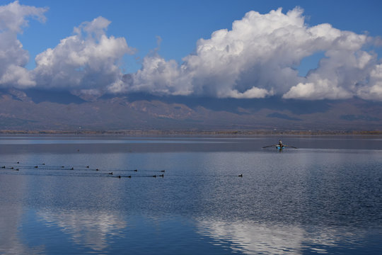 Doiran Lake seen from the town of Stari Doiran, Macedonia. Sunny autumn day, poor fisherman with old fishing boat in the calm lake. Greece on other side of the lake