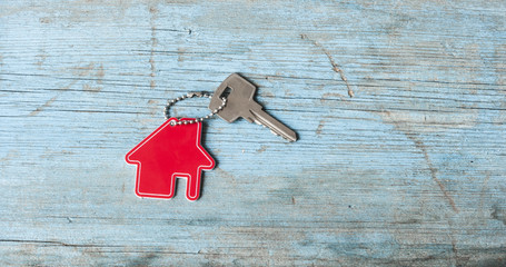 Key with house icon on wooden background