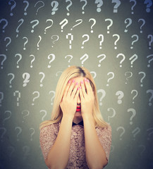 Woman with many questions and no answer covering her eyes with hands avoiding problem 