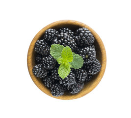 Blackberries with mint leaf in a wooden bowl with copy space for text. Ripe and tasty blackberry isolated on white background. Top view.