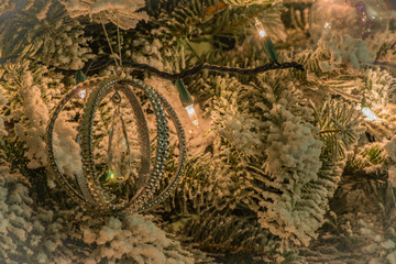 Ornaments hanging on the tree with lights and snow 