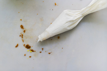 Frosting pastry bag with bread crumbs on cutting mat.
