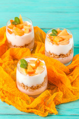 Persimmon creamy trifle in beautiful glasses, fresh ripe fruit slices on mint wooden background. Healthy vegetarian food. Delicious dessert. Close up photography. Selective focus.