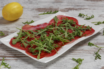 Bresaola con rucola fresca su piatto bianco