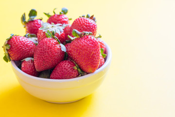 Strawberries in white bowl on yellow background
