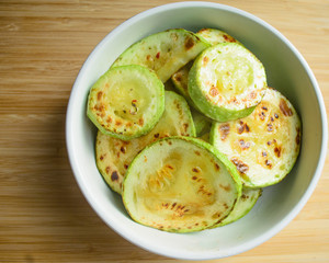 Fried zucchini in white dish on wooden table