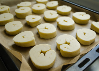 Raw sweet puff pastry bun ears on  parchment paper on baking sheet
