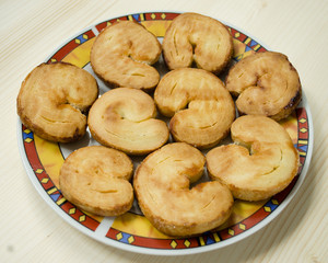 Sweet puff pastry bun ears on a colorful plate on wooden table