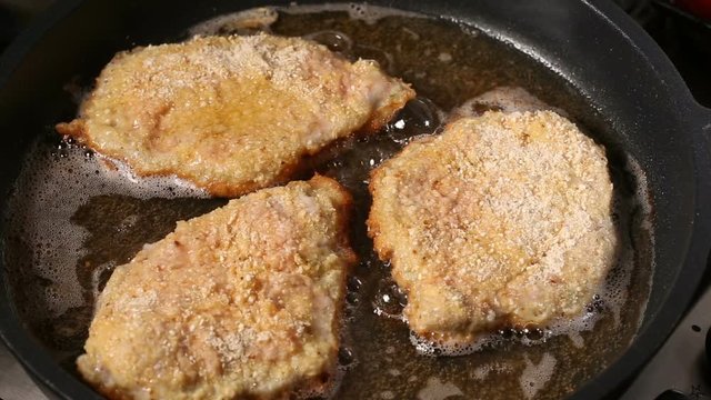 Frying pork meat coated with breadcrumbs in a pan