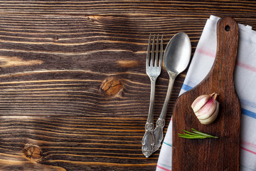 Food cooking background with wooden cutting board, cutlery and spices. Top view with copy space.