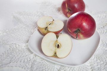 the Red apples and halves of apples on a plate on a lace napkin