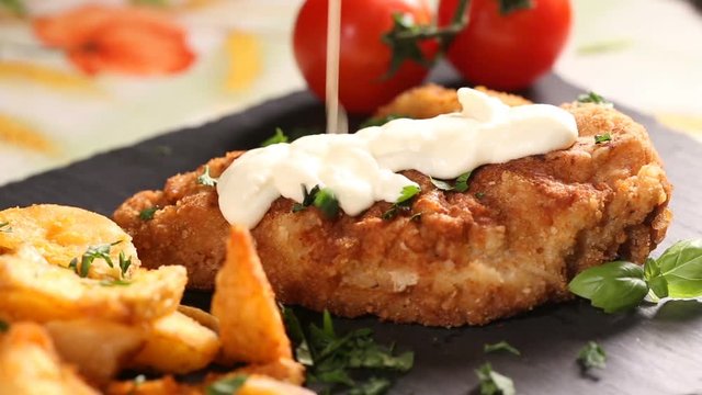 Pouring white sauce over pork schnitzel with white sauce