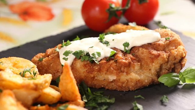 Sprinkling fresh parsley over pork schnitzel with white sauce