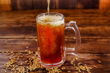 Indoor view of glass of beer with wheat in the base on a wooden table on a dark pub