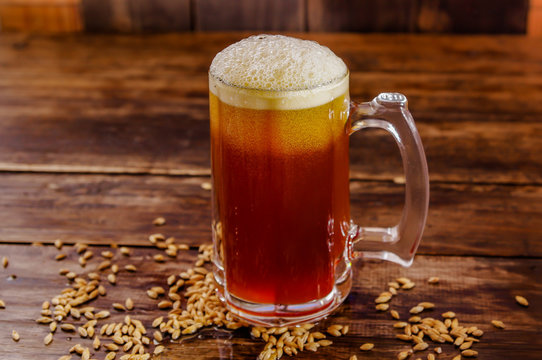 Indoor view of glass of beer with wheat in the base on a wooden table on a blurred background