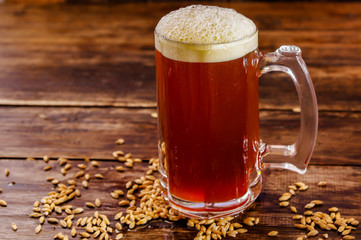 Indoor view of glass of beer with wheat in the base on a wooden table on a blurred background