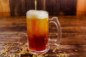 Indoor view of glass of beer with wheat in the base on a wooden table on a blurred background