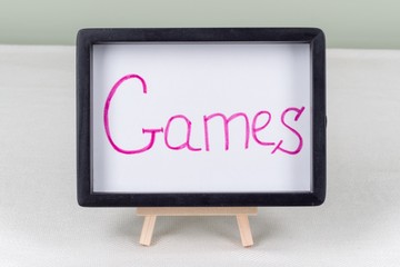 Text word games, in black frame, on white table.