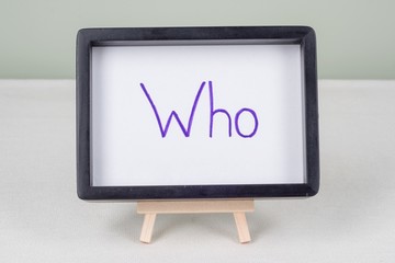 Text word WHO, in black frame, on white table.