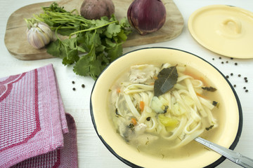Appetizing chicken soup with noodles, with the addition of potatoes, carrot greens and bay leaf.
