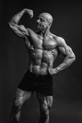 Professional strong bodybuilder athletic man posing front biceps in studio