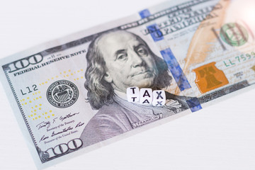 Tax word with money - american dollars, on white background. Concept - payment of taxes