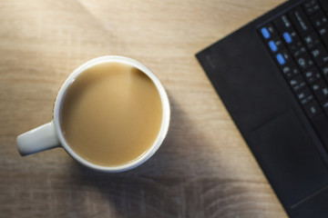 coffee mug with milk next to a laptop, work at home