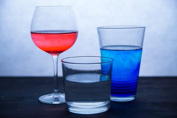 Three glasses of colored water on a white and blue background