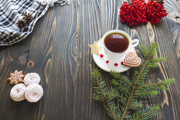 view from above on a wooden table with marshmallow, berries, cookies, pine branch and tea set