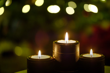 Obraz na płótnie Canvas Three candles with Background Christmas Tree Lights