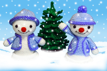 two cheerful snowman toy in the snow near the Christmas tree