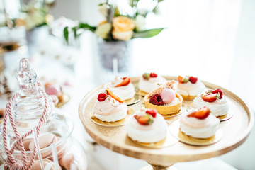 Delicious wedding reception candy bar dessert table full with cakes and sweets and a flower vase with hydrangeas on the background of an exquisite restaurant.