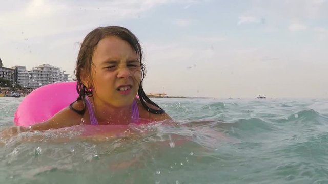 The child learns to swim. A little girl on an inflatable circle is swimming in the sea.