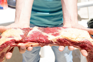 Man showing a piece of Argentine Asado Raw meat