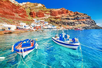 Poster Greece. Breathtaking beautiful landscape of two fishing boats anchored to quay in fascinating blue water at the amazing old port panorama in Oia Ia village on Santorini Greek island in Aegean sea. © Feel good studio
